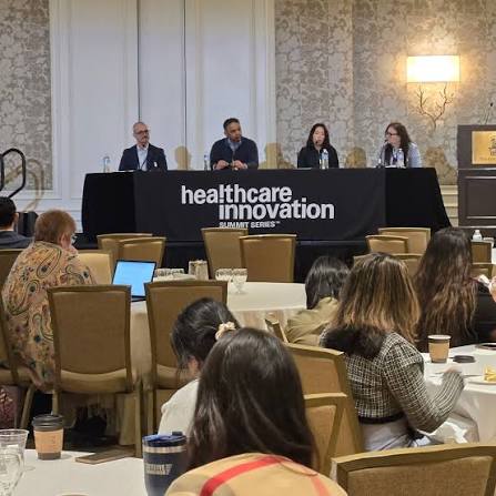 A panel discussion in front of a seated audience at a community event